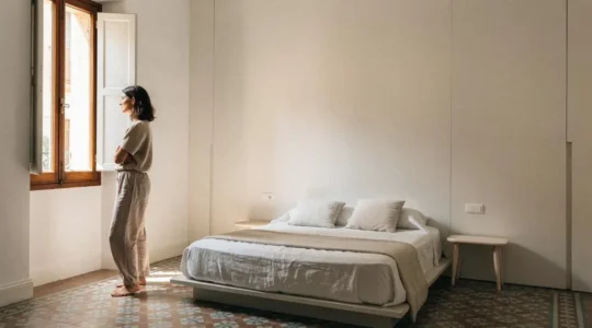 Pared de dormitorio en un piso español con almacenaje integrado invisible, luz natural y aspecto minimalista