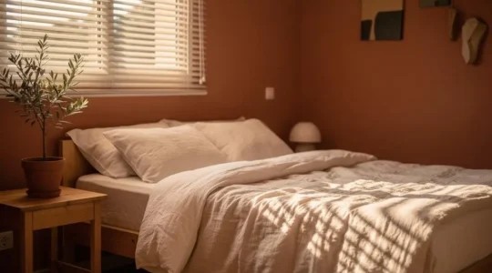 Dormitorio luminoso y sereno de un piso español con persianas entreabiertas y textiles naturales, transmitiendo descanso sin grandes lujos