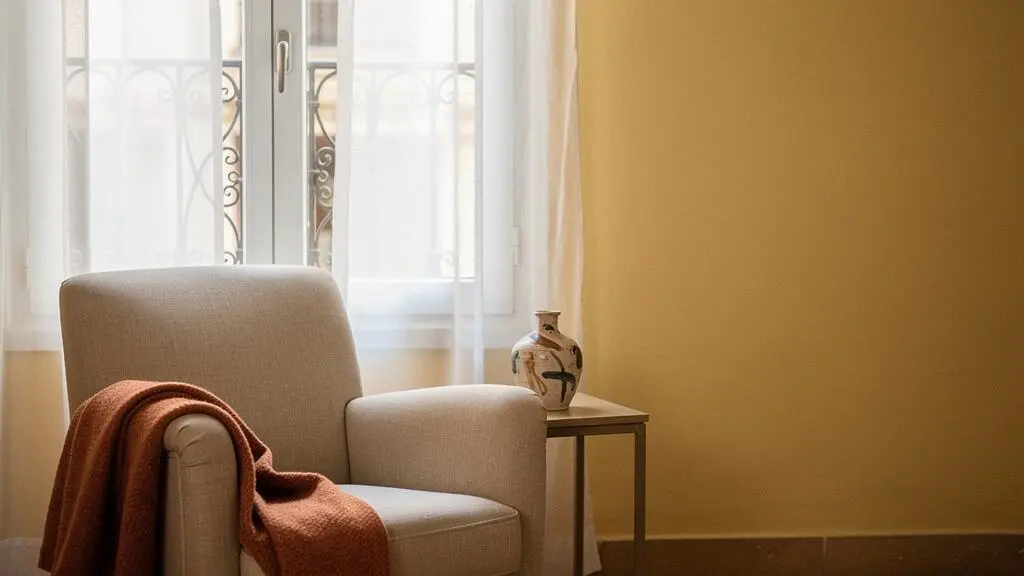 Salón acogedor con orientación norte decorado en tonos ocres cálidos y textiles de lino junto a una ventana con luz fría filtrada