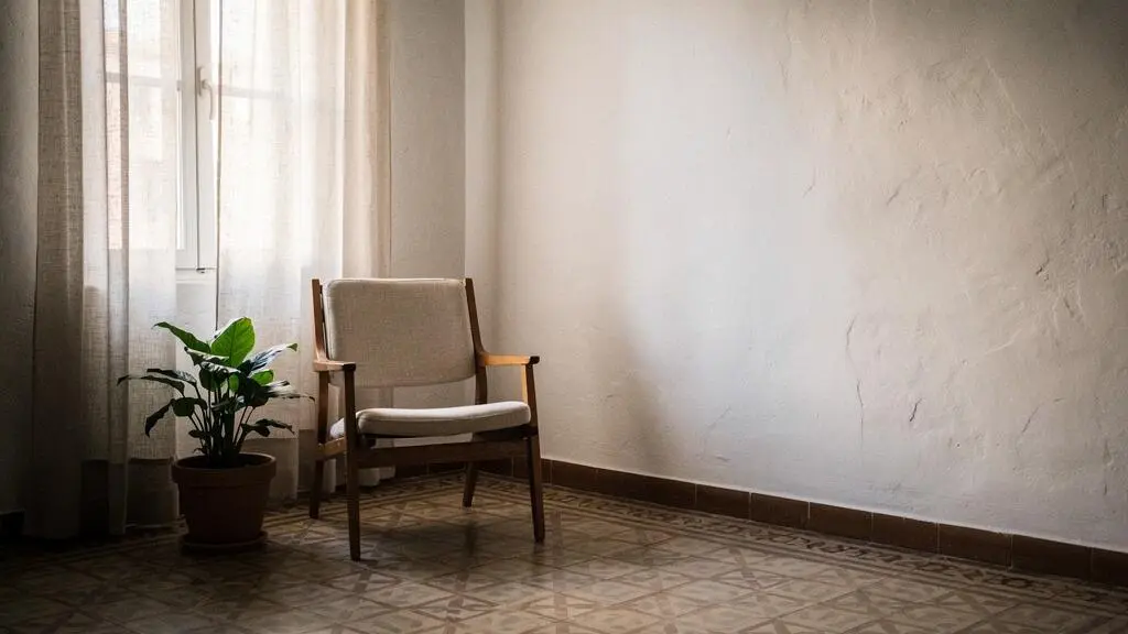 Salón español luminoso con paredes en blanco cálido reflejando la luz natural de una ventana orientada al norte