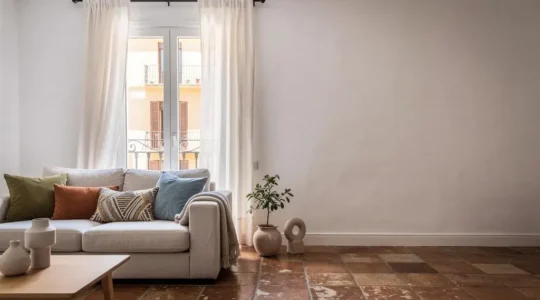 Salón luminoso de un piso español de 70 metros cuadrados transformado con cortinas de lino y cojines de temporada