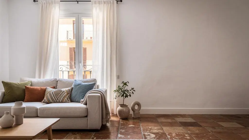 Salón luminoso de un piso español de 70 metros cuadrados transformado con cortinas de lino y cojines de temporada