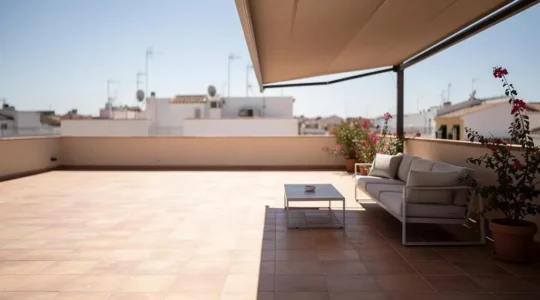 Terraza española sombreada por un toldo retráctil que reduce la temperatura exterior en un día soleado de verano