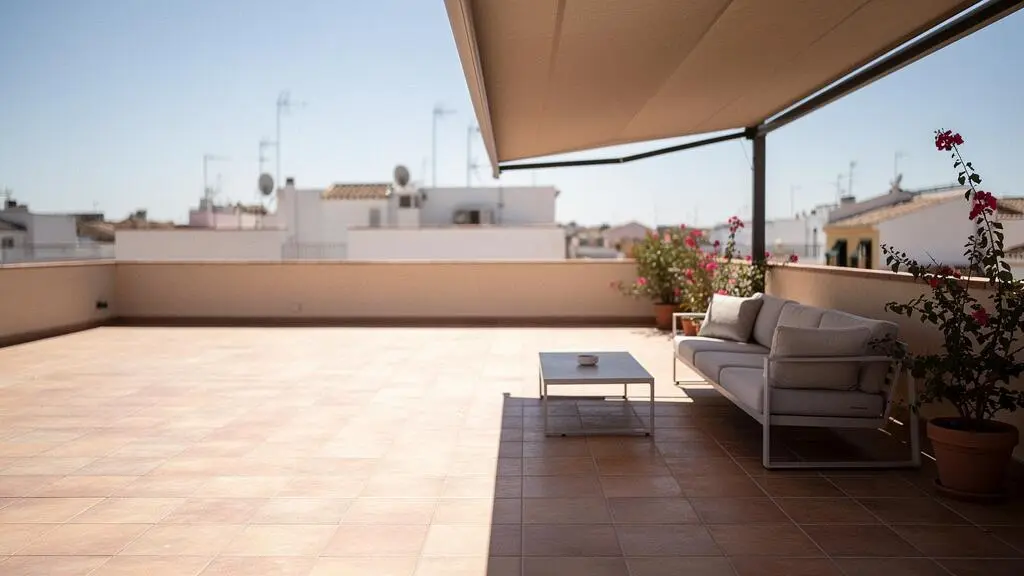 Terraza española sombreada por un toldo retráctil que reduce la temperatura exterior en un día soleado de verano