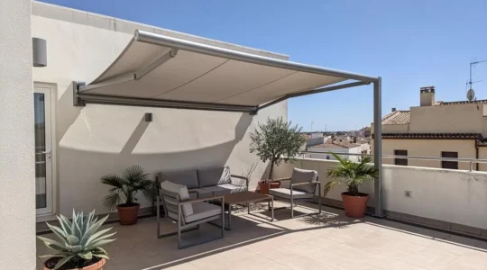 Vista amplia de una terraza contemporánea española con toldo dos aguas instalado, mobiliario de exterior y luz natural mediterránea