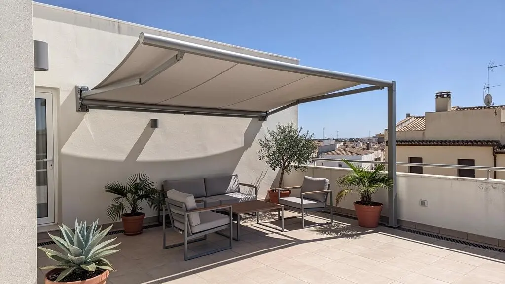 Vista amplia de una terraza contemporánea española con toldo dos aguas instalado, mobiliario de exterior y luz natural mediterránea