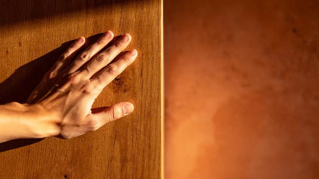 Mano acariciando una superficie de madera de roble aceitada en un interior español luminoso y cálido
